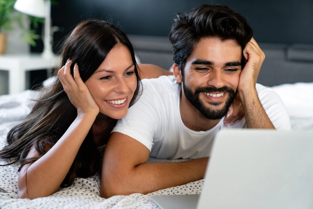 Happy young man and woman is having fun in bed together